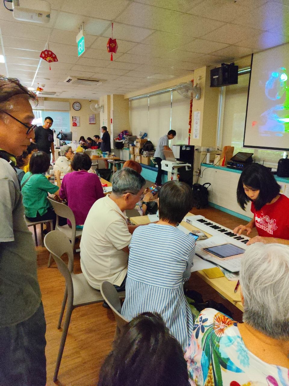Seniors gathered around a keyboard in a community access workshop