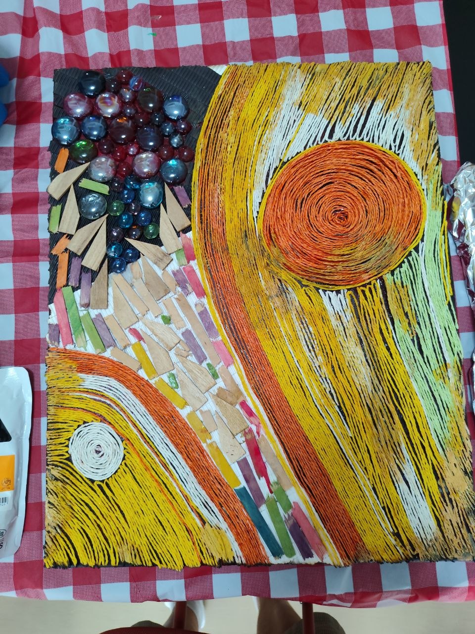 A mixed-media collage made with swirling fibres and glass pebbles